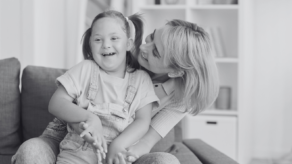 A woman hugging her disabled daughter whilst both are smiling